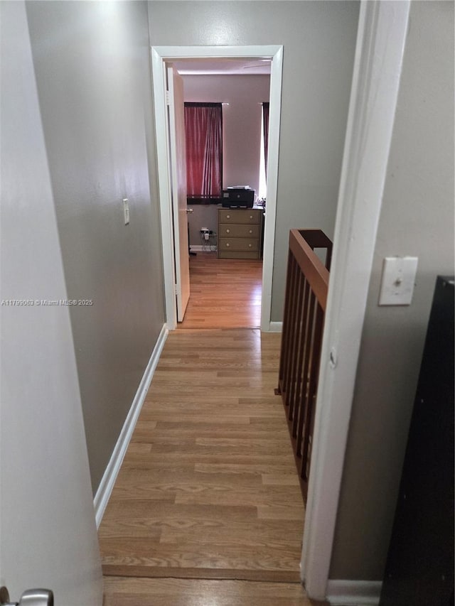 hallway featuring light wood-type flooring and baseboards