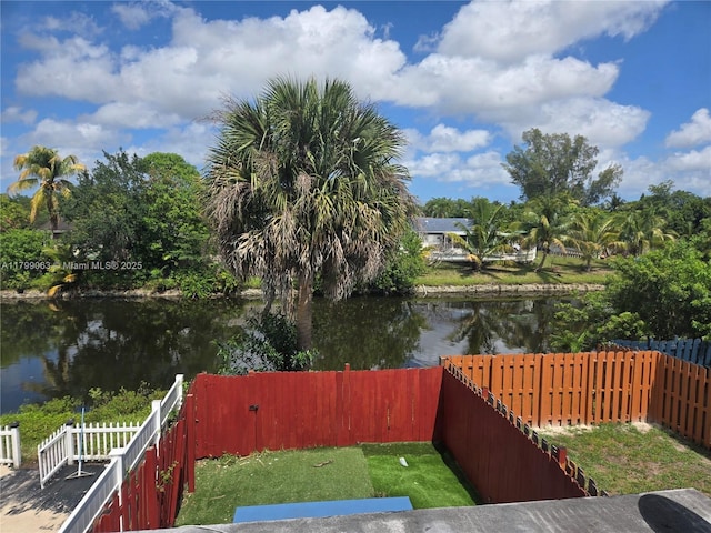 fenced backyard featuring a water view