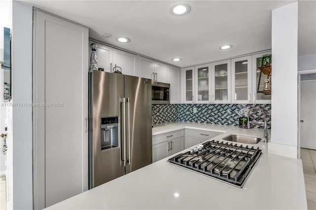 2201 Brickell Ave Unit 77, Miami, FL 33129 - kitchen with appliances with stainless steel finishes, a sink, light countertops, glass insert cabinets, and decorative backsplash