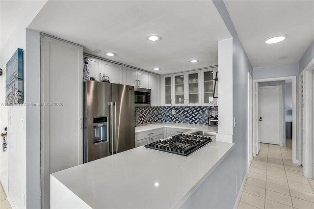 2201 Brickell Ave Unit 77, Miami, FL 33129 - kitchen with appliances with stainless steel finishes, a sink, light tile patterned floors, glass insert cabinets, and light countertops