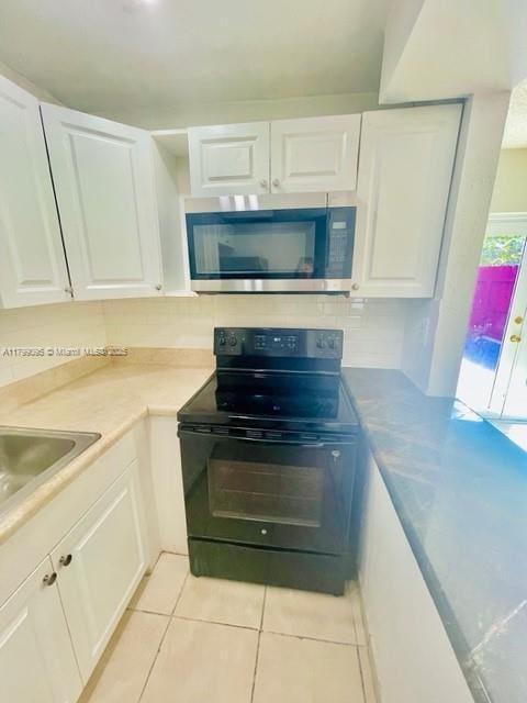3672 SW 59th Ave Unit 7, Davie, FL 33314 - kitchen featuring stainless steel microwave, electric range, white cabinets, light tile patterned floors, and light countertops