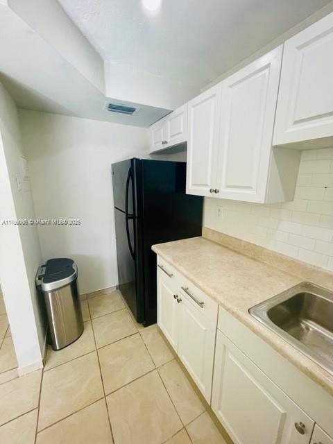 3672 SW 59th Ave Unit 7, Davie, FL 33314 - kitchen with light tile patterned floors, white cabinets, light countertops, freestanding refrigerator, and backsplash