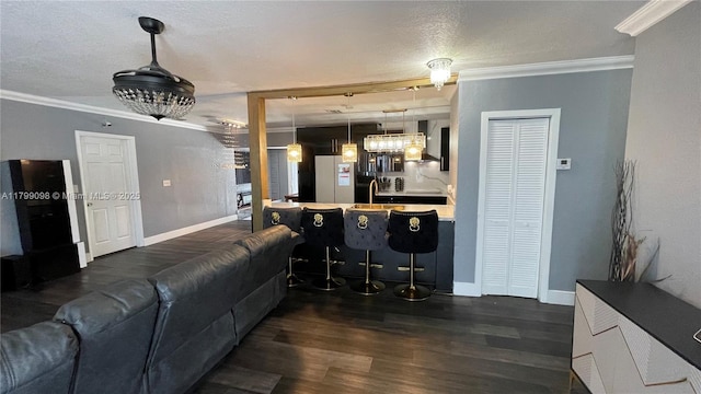 living room with ornamental molding, baseboards, dark wood finished floors, and a chandelier