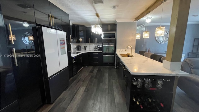 kitchen featuring a sink, dark cabinets, a peninsula, stainless steel microwave, and light countertops