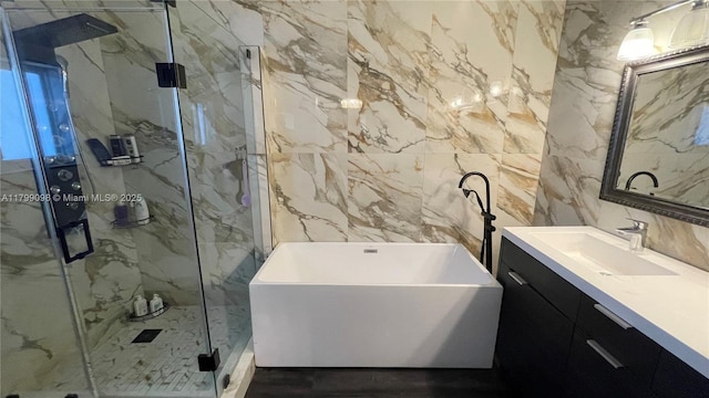 bathroom featuring a marble finish shower, tile walls, vanity, and a freestanding tub