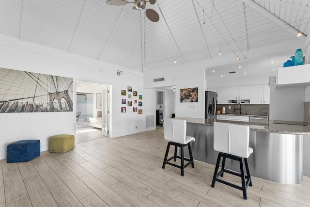 5715 Bayberry Ln, Tamarac, FL 33319 - kitchen with high vaulted ceiling, stainless steel refrigerator with ice dispenser, white cabinetry, a kitchen breakfast bar, and a ceiling fan
