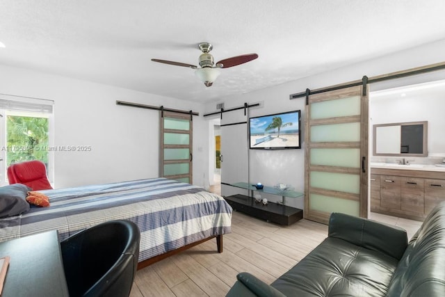 5715 Bayberry Ln, Tamarac, FL 33319 - bedroom with a barn door, light wood-style floors, a sink, and ensuite bathroom