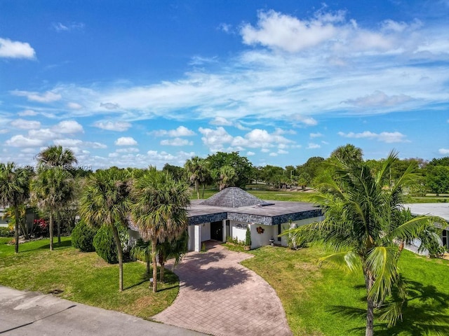 5715 Bayberry Ln, Tamarac, FL 33319 - view of front facade with decorative driveway, a front lawn, a garage, and view of wooded area
