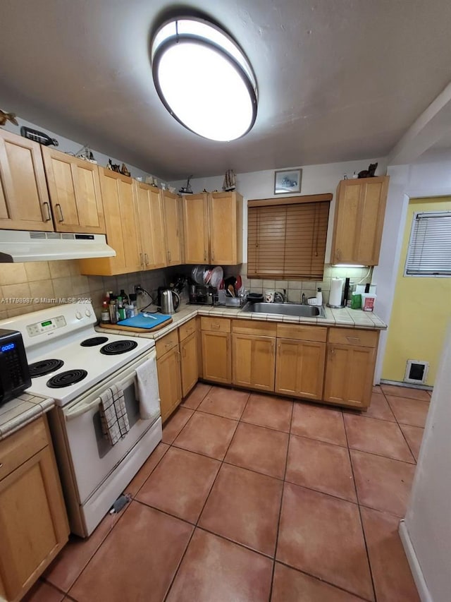 2415 Garfield St, Hollywood, FL 33020 - kitchen with white range with electric stovetop, under cabinet range hood, tile countertops, and a sink