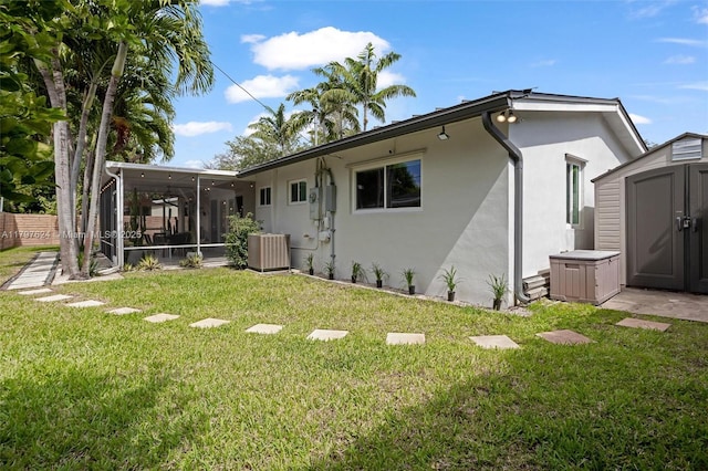 950 NE 88th St, Miami, FL 33138 - rear view of property featuring a sunroom, a storage unit, stucco siding, a lawn, and an outbuilding