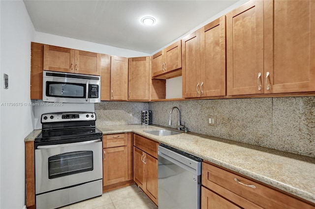 2840 NE 14th St Cswy Unit 408A, Pompano Beach, FL 33062 - kitchen featuring appliances with stainless steel finishes, a sink, tasteful backsplash, light tile patterned floors, and brown cabinets