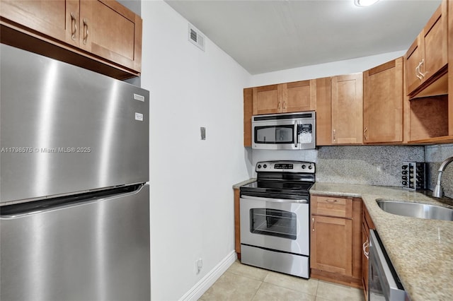 2840 NE 14th St Cswy Unit 408A, Pompano Beach, FL 33062 - kitchen featuring appliances with stainless steel finishes, a sink, light tile patterned floors, baseboards, and brown cabinetry