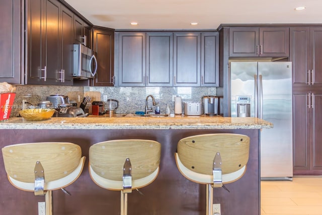 kitchen with stainless steel appliances, light stone counters, backsplash, and recessed lighting