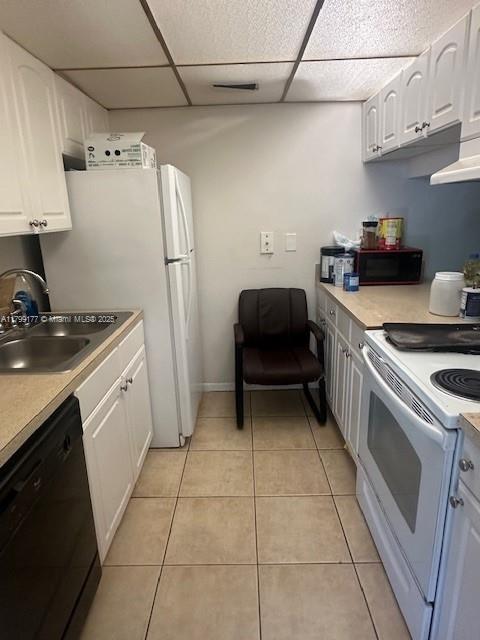 1900 N Congress Ave Unit 305, West Palm Beach, FL 33401 - kitchen featuring black appliances, a sink, white cabinetry, light tile patterned flooring, and a paneled ceiling