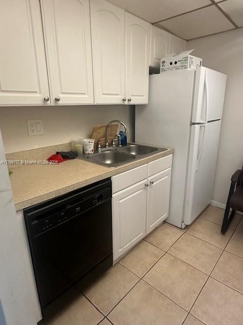 1900 N Congress Ave Unit 305, West Palm Beach, FL 33401 - kitchen with black dishwasher, a sink, light tile patterned floors, and white cabinets