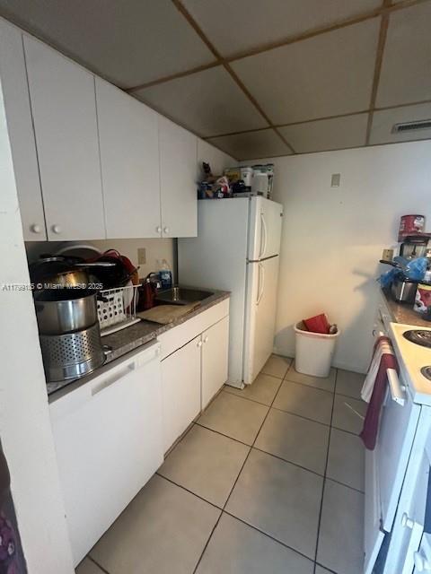 1820 N Congress Ave Unit 405, West Palm Beach, FL 33401 - kitchen featuring white appliances, white cabinets, a paneled ceiling, light tile patterned floors, and a sink