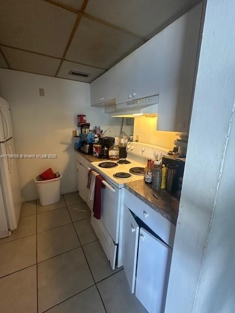 1820 N Congress Ave Unit 405, West Palm Beach, FL 33401 - kitchen featuring white electric stove, under cabinet range hood, white cabinetry, light tile patterned floors, and a drop ceiling