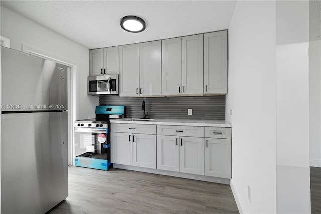 2571 NW 139th St, Opa-Locka, FL 33054 - kitchen featuring stainless steel appliances, a sink, gray cabinets, light wood-type flooring, and decorative backsplash