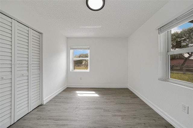 2571 NW 139th St, Opa-Locka, FL 33054 - unfurnished bedroom with a textured ceiling, multiple windows, wood finished floors, and baseboards