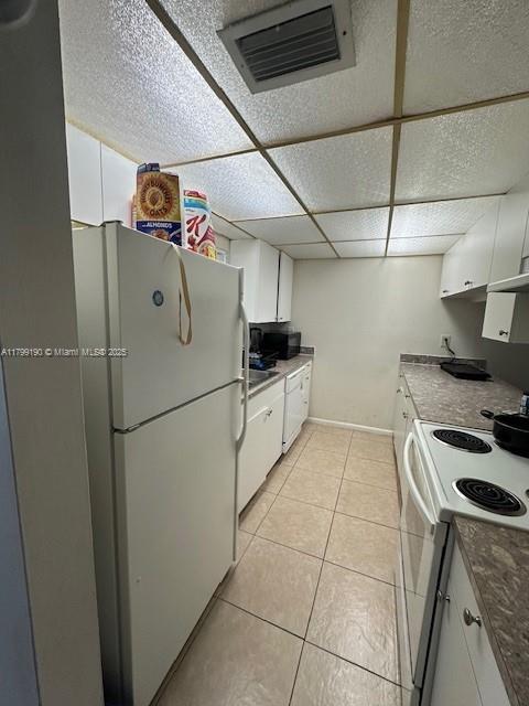 2000 N Congress Ave Unit 411, West Palm Beach, FL 33401 - kitchen featuring white appliances, white cabinets, light tile patterned flooring, under cabinet range hood, and baseboards