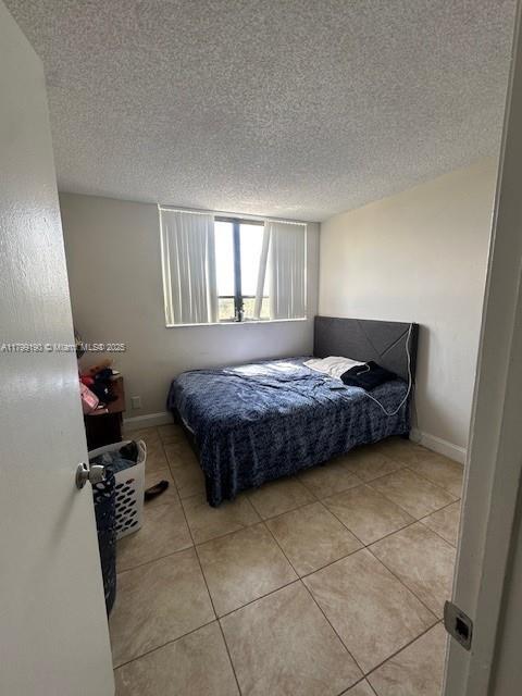 2000 N Congress Ave Unit 411, West Palm Beach, FL 33401 - bedroom with a textured ceiling, light tile patterned floors, and baseboards