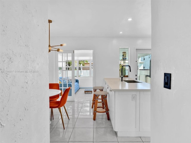 729 85th St, Miami Beach, FL 33141 - kitchen with a sink, a textured wall, light countertops, light tile patterned flooring, and a chandelier