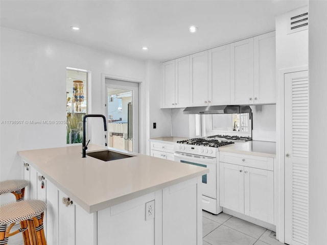 729 85th St, Miami Beach, FL 33141 - kitchen with white gas range, a sink, under cabinet range hood, white cabinets, and recessed lighting