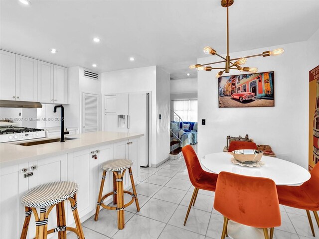 729 85th St, Miami Beach, FL 33141 - kitchen featuring under cabinet range hood, recessed lighting, a sink, a breakfast bar, and light countertops