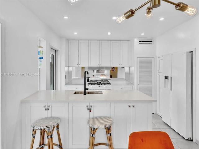 729 85th St, Miami Beach, FL 33141 - kitchen featuring a sink, light countertops, white cabinetry, light tile patterned flooring, and recessed lighting