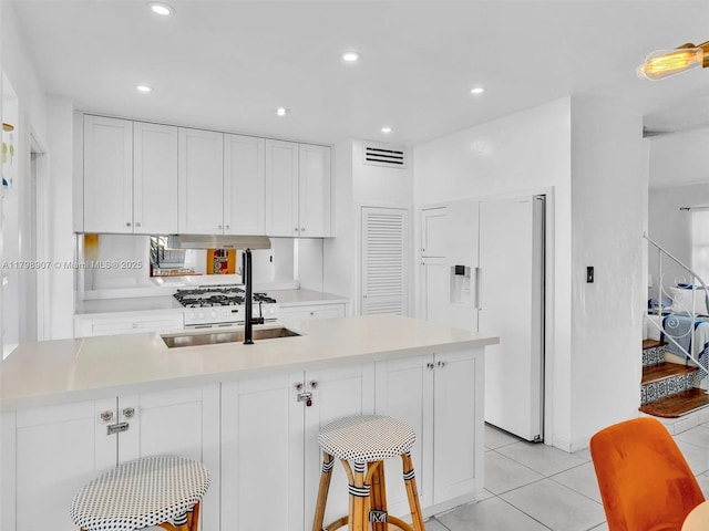 729 85th St, Miami Beach, FL 33141 - kitchen with white fridge with ice dispenser, a sink, light countertops, white cabinets, and light tile patterned flooring