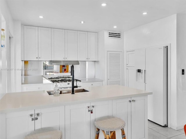 729 85th St, Miami Beach, FL 33141 - kitchen with white cabinets, white fridge with ice dispenser, light countertops, recessed lighting, and light tile patterned flooring