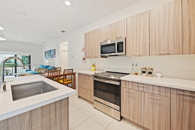 kitchen featuring stainless steel appliances, light brown cabinets, modern cabinets, open floor plan, and recessed lighting