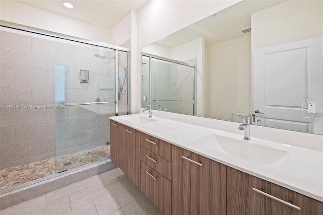 full bath with a shower stall, double vanity, tile patterned flooring, and toilet