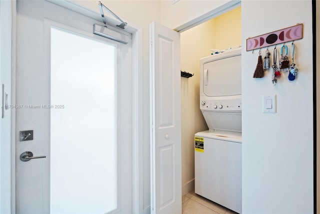 clothes washing area featuring stacked washer and clothes dryer and light tile patterned flooring