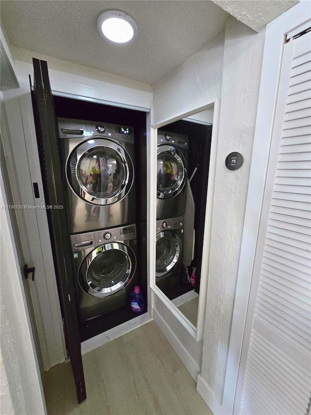 laundry room featuring stacked washing machine and dryer, wood finished floors, and a textured ceiling