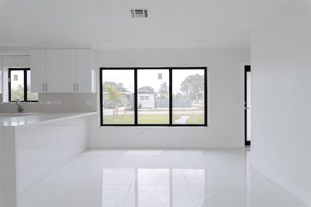 17940 NW 13th Ct, Miami Gardens, FL 33169 - kitchen with light marble finish floors, light countertops, white cabinets, and baseboards