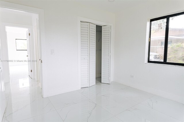 17940 NW 13th Ct, Miami Gardens, FL 33169 - unfurnished bedroom featuring light marble finish flooring, baseboards, and a closet