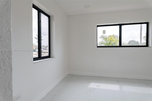 17940 NW 13th Ct, Miami Gardens, FL 33169 - empty room featuring healthy amount of natural light, baseboards, and light marble finish flooring