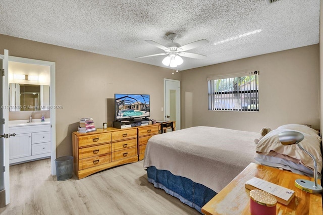 1930 W Oak Knoll Cir, Davie, FL 33324 - bedroom featuring light wood-type flooring, connected bathroom, a sink, a textured ceiling, and a ceiling fan