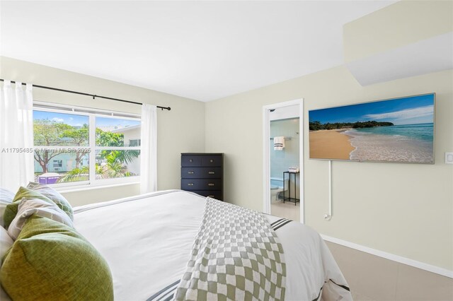 bedroom featuring baseboards and ensuite bath
