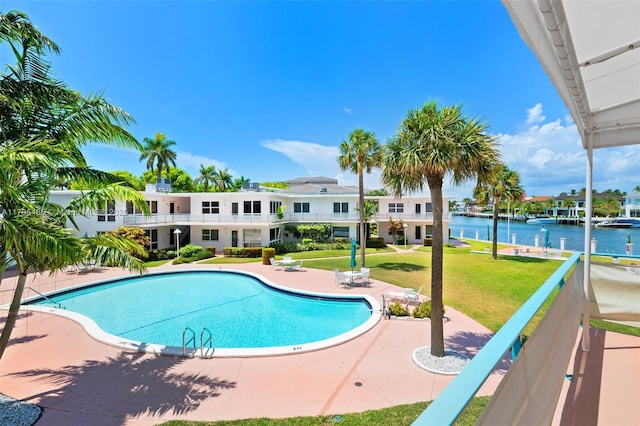 community pool with a water view, a patio, and a lawn