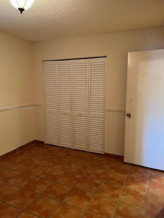 10600 SW 71st Ln Unit 10600, Miami, FL 33173 - unfurnished bedroom with a closet, tile patterned floors, a textured ceiling, and baseboards