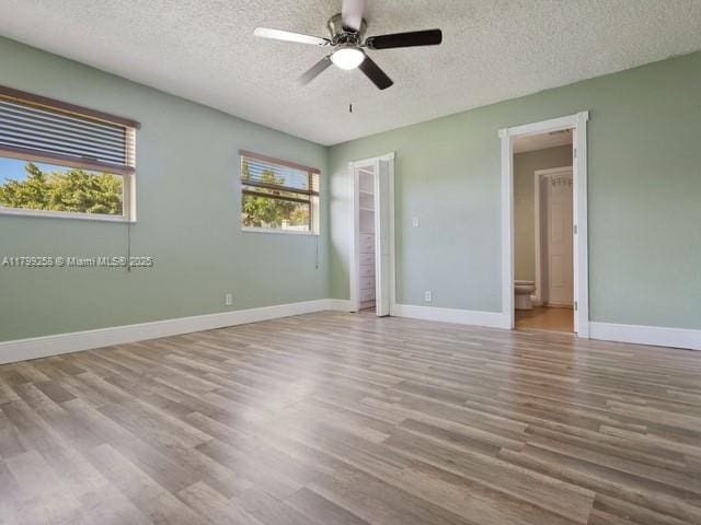 2650 NW 67th Ter, Margate, FL 33063 - unfurnished bedroom with a textured ceiling, wood finished floors, ceiling fan, and ensuite bathroom