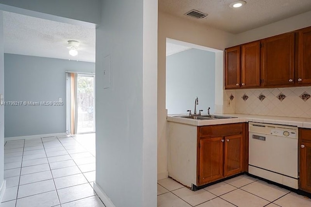 5154 Breckenridge Pl Unit 47, West Palm Beach, FL 33417 - kitchen featuring white dishwasher, a sink, decorative backsplash, light tile patterned floors, and brown cabinetry
