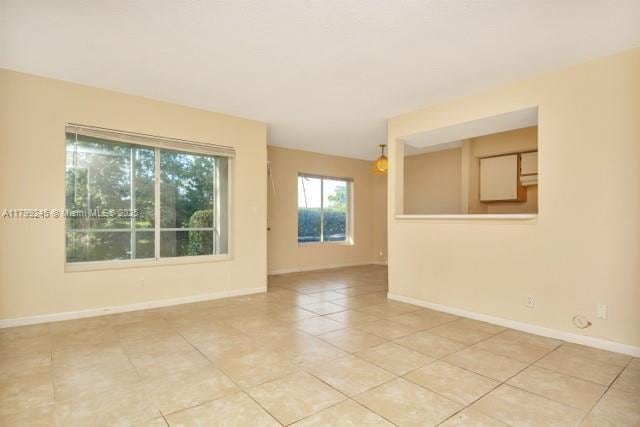 unfurnished room with light tile patterned flooring and baseboards