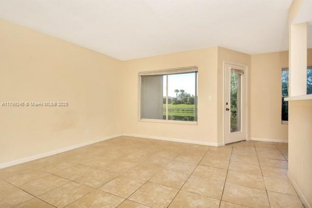 empty room featuring light tile patterned flooring and baseboards