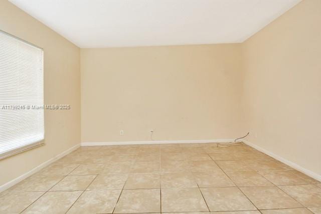 empty room featuring light tile patterned flooring and baseboards