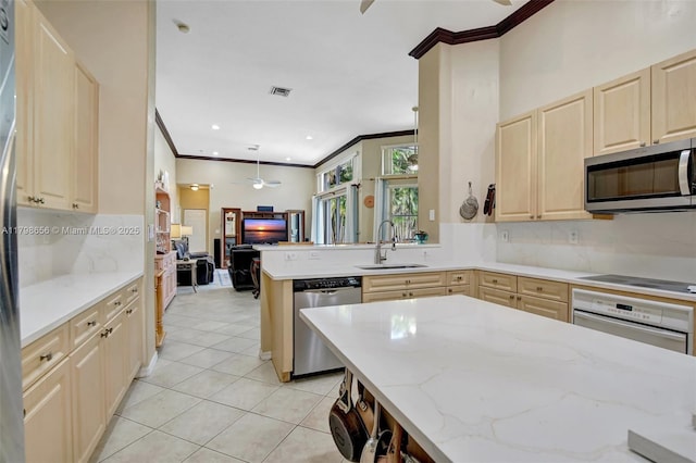 kitchen with appliances with stainless steel finishes, light brown cabinets, a sink, crown molding, and a peninsula