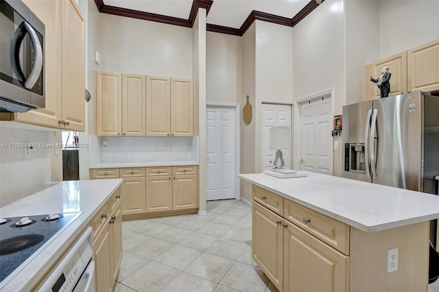 kitchen with light brown cabinets, stainless steel appliances, crown molding, a towering ceiling, and light countertops