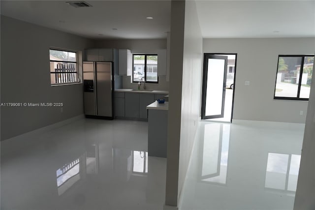 kitchen featuring stainless steel fridge, light countertops, a sink, gray cabinetry, and modern cabinets